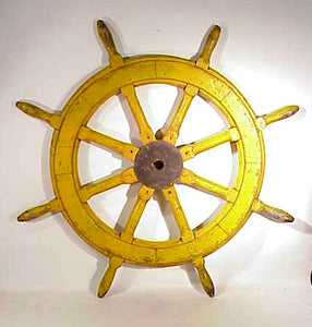Antique ship's wheel in old yellow paint