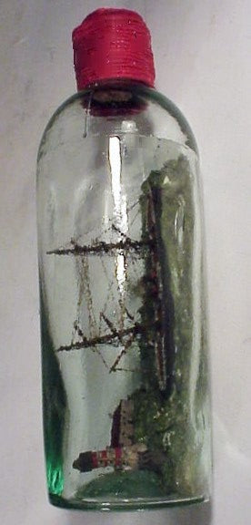 Antique ship-in-bottle with lighthouse scene.